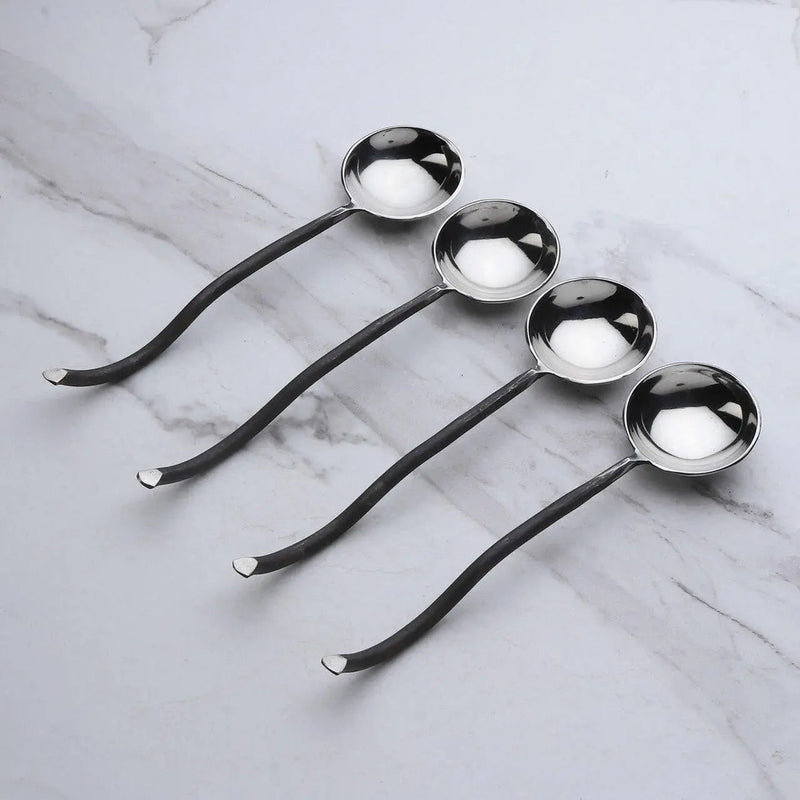 Set of four metal spoons on a marble surface
