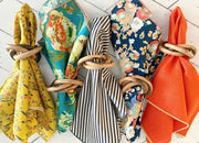 Set of colorful napkins tied with wooden rings on a light wooden surface