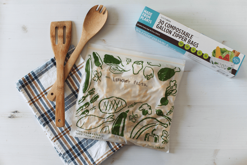 Compostable gallon zipper bags with wooden utensils and a box on a white surface