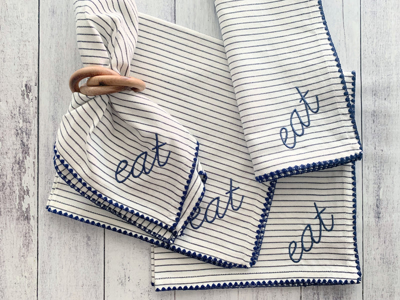 Striped towels with 'eat' embroidery on a wooden surface