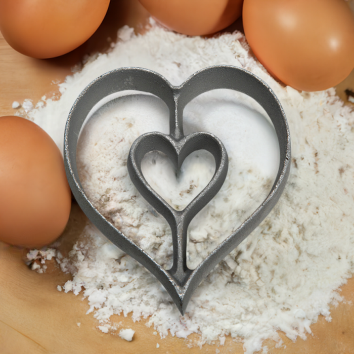 Heart shaped aluminum rosette iron in flour with eggs