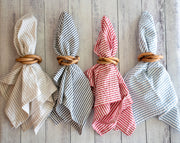 Four folded napkins with wooden rings on a wooden surface