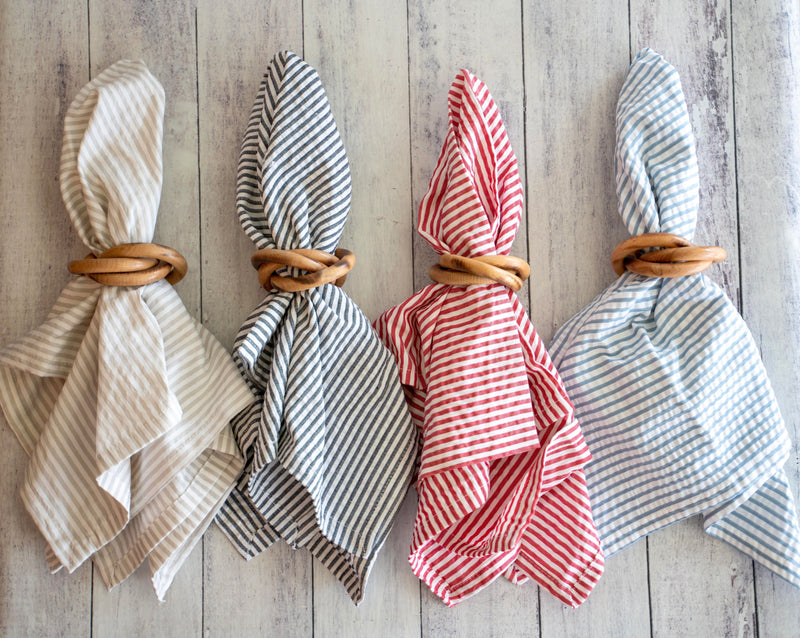 Four folded napkins with wooden rings on a wooden surface