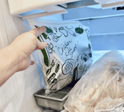 Hand reaching for a package of chicken in a refrigerator.