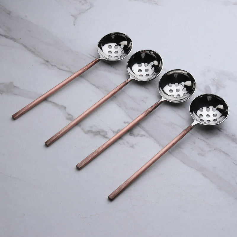 Four slotted spoons on marble background