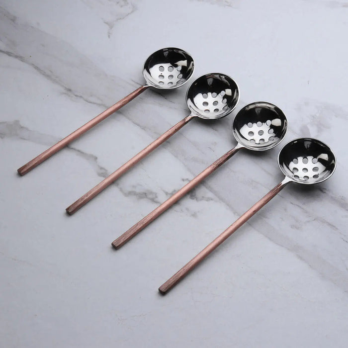 Four slotted spoons on marble background