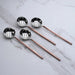 Set of four ladle spoons with copper handles on a marble surface
