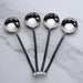 Four black-handled spoons with silver bowls on a marble surface