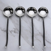 Four silver ladles on a marble surface