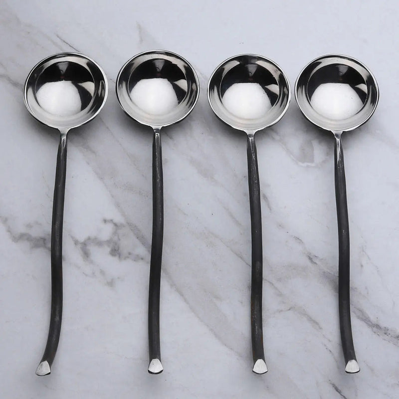 Four silver ladles on a marble surface
