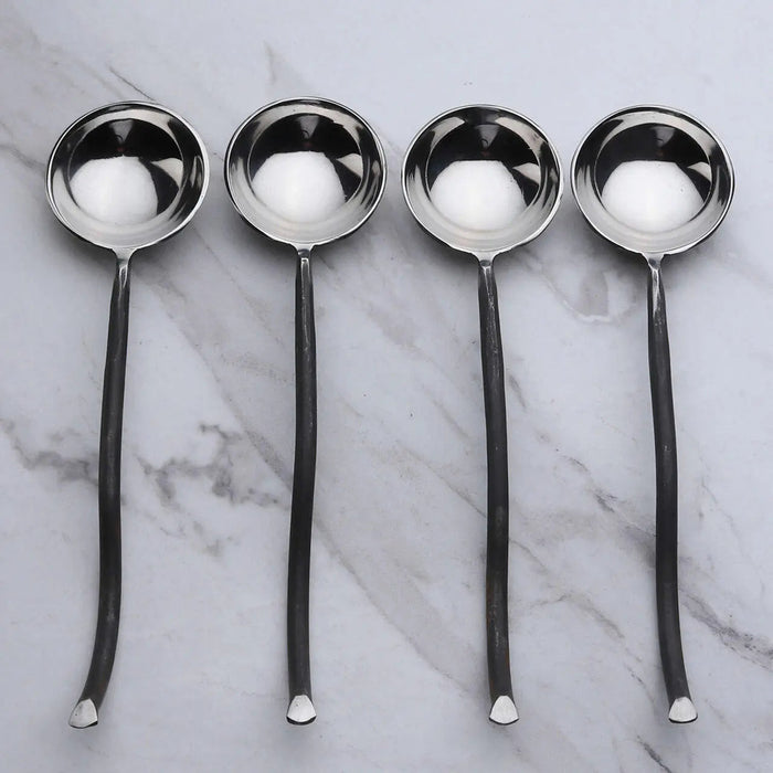 Four silver ladles on a marble surface