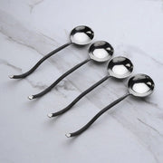 Set of four metal spoons on a marble surface
