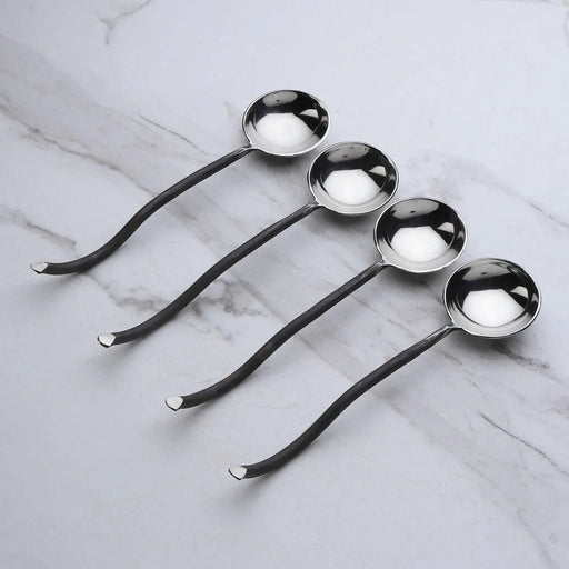 Set of four metal spoons on a marble surface
