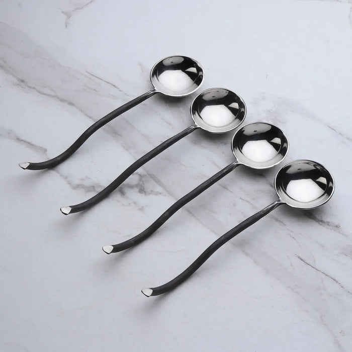 Set of four metal spoons on a marble surface