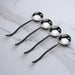 Set of four metal spoons on a marble surface