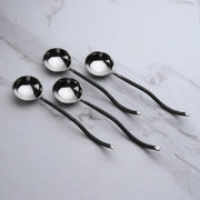 Set of four silver spoons on a marble surface