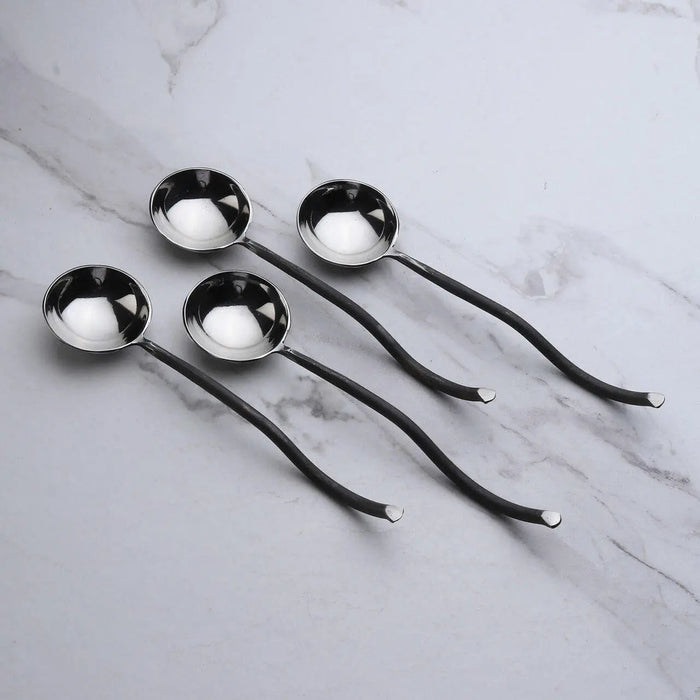 Set of four silver spoons on a marble surface