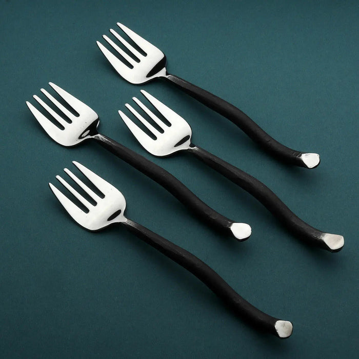 Set of five silver cake forks with black handles on a teal background