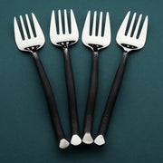Four silver forks with black handles on a teal background