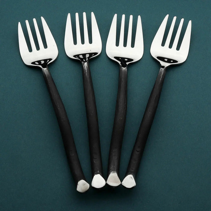 Four silver forks with black handles on a teal background