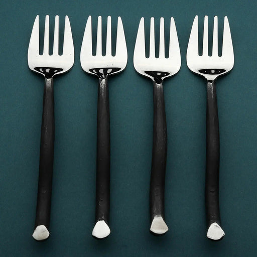 Four silver forks with black handles on a teal background