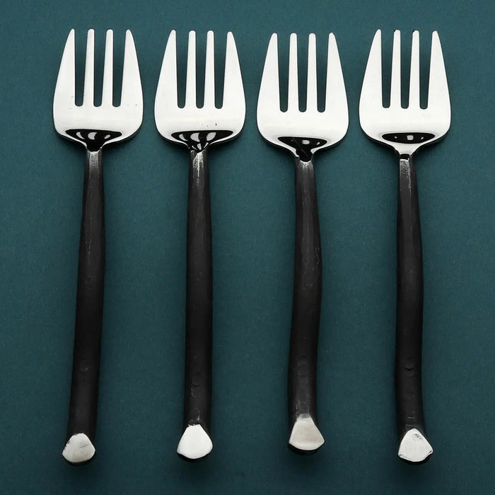 Four silver forks with black handles on a teal background