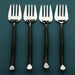 Four silver forks with black handles on a teal background