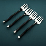 Four black-handled forks on a dark green background