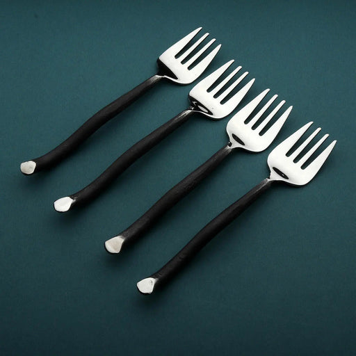 Four black-handled forks on a dark green background
