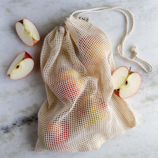 Mesh produce bag with apples on a marble surface